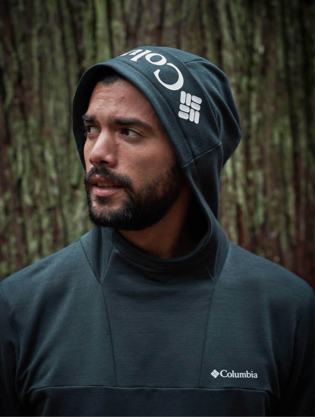 A man gazing to the side standing in the woods